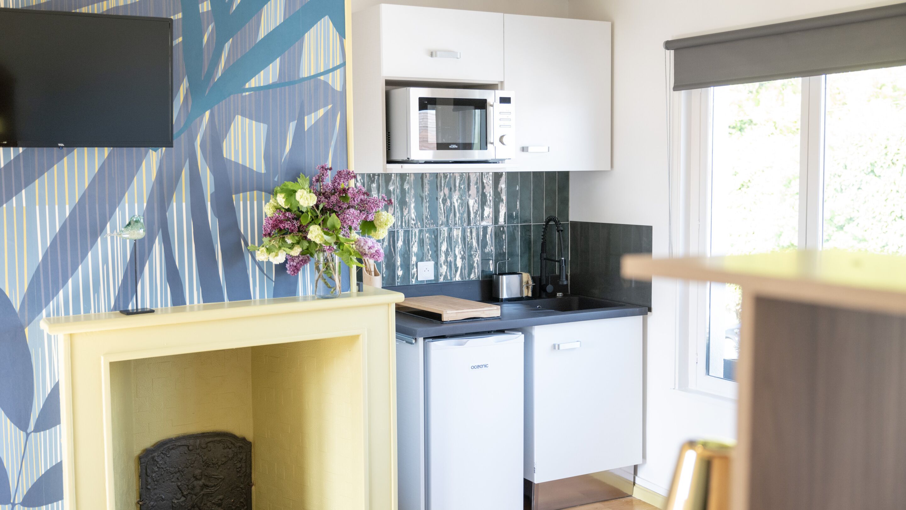 A modern kitchen with a microwave, sink, and a decorative wall with a geometric pattern.