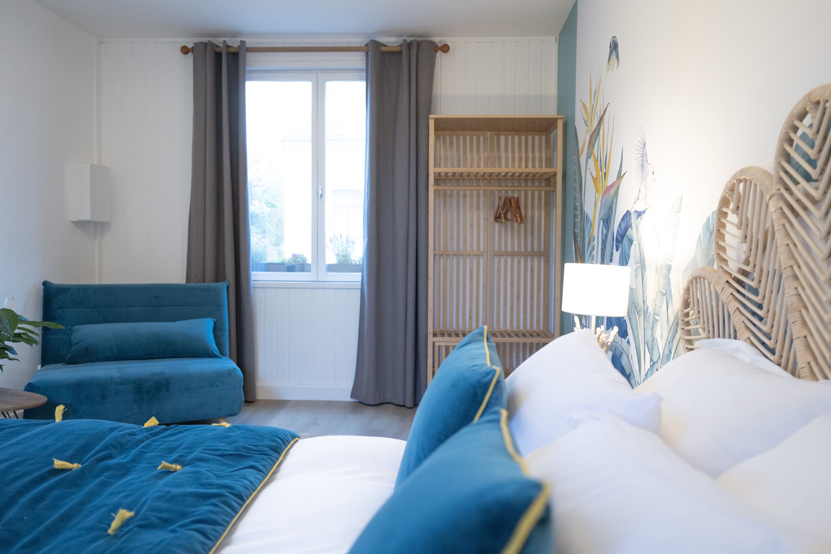 A bedroom with a bed, a sofa, a wardrobe, and a window with curtains.