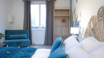 A bedroom with a bed, a sofa, a wardrobe, and a window with curtains.