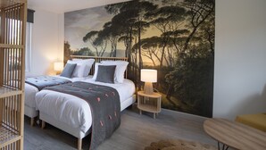 Un dormitorio con una cama grande, dos mesitas de noche, una pequeña silla de madera y un mural grande en la pared.