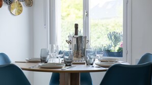 Een gedekte eettafel met borden, glazen en bestek, met een champagnefles in het midden.