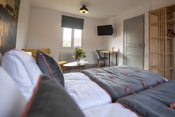 Un dormitorio con cama, escritorio, silla y televisor en la pared.