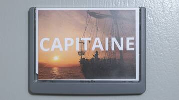 Een lijst met een foto van een schip bij zonsondergang, met daarop de tekst 'CAPITAINE'.