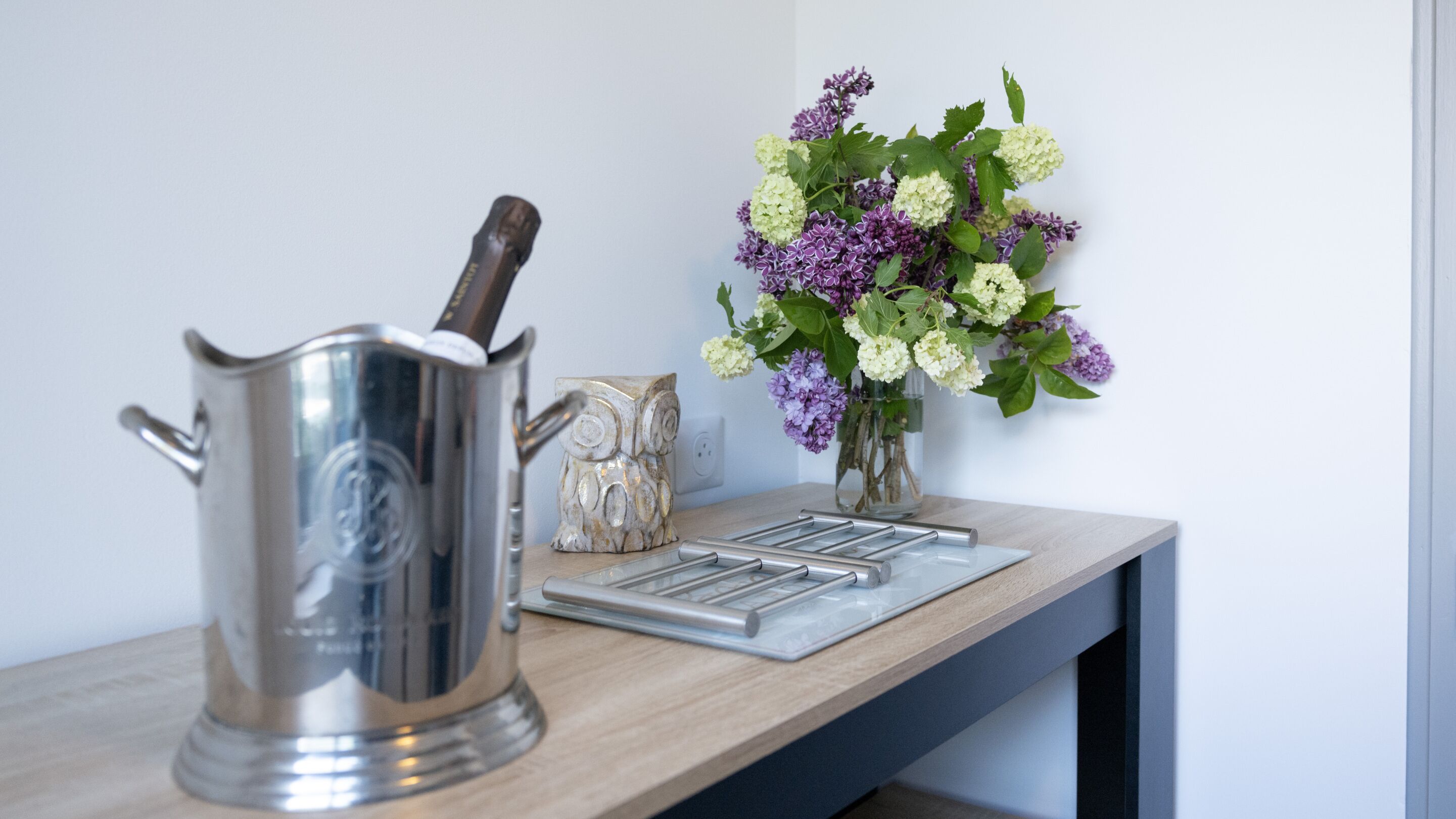 Un plan de travail de cuisine avec une bouilloire en acier inoxydable, un bloc à couteaux et un vase rempli de fleurs.