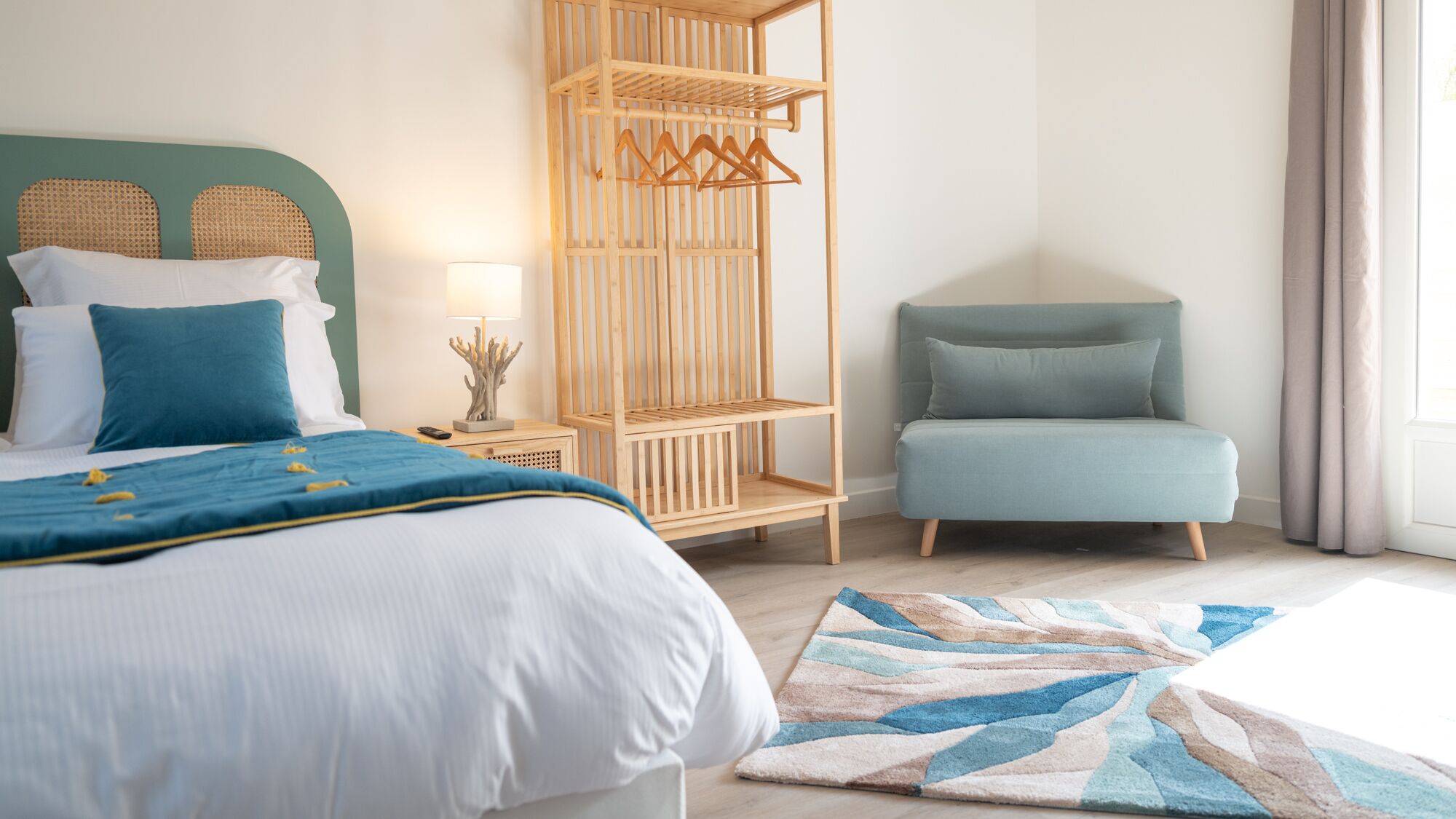 Una habitación de hotel moderna con una cama, un espacio de descanso, un estante de madera y vistas al exterior.