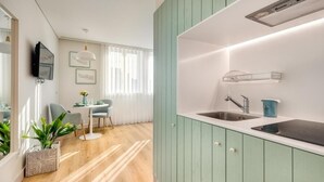 A modern kitchen with light green cabinets, a built-in stove, and a sink. - 7 Bridges Estúdios (Porto)