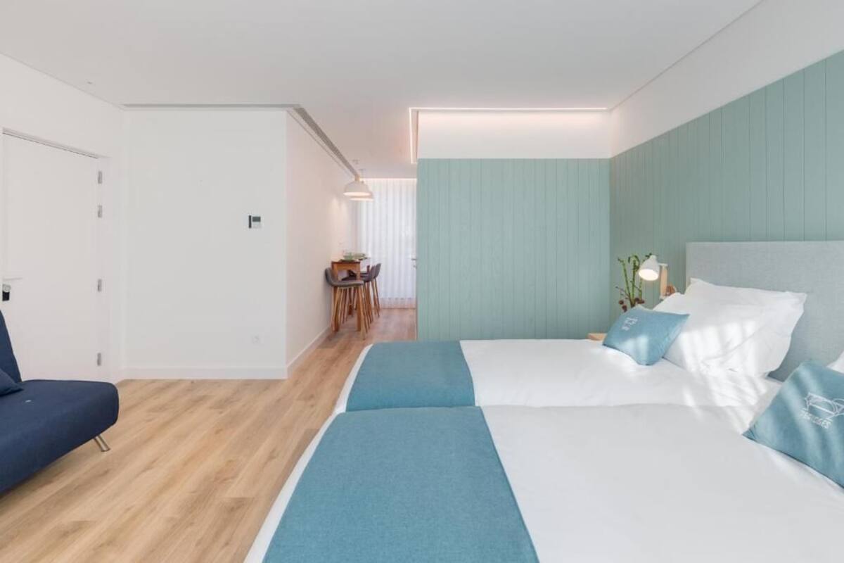 Ein modernes Hotelzimmer mit einem großen Bett, einer Sitzecke mit Tisch und Blick auf den Flur.