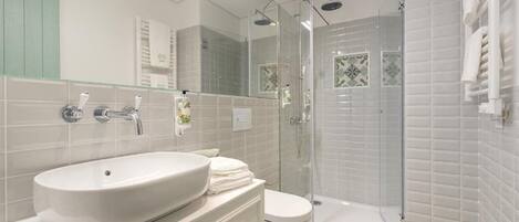 Un bany modern amb un lavabo gran, vàter i dutxa amb envàs de vidre.