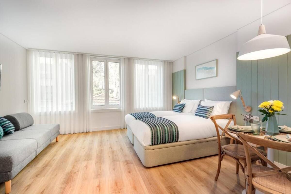 Ein modernes Schlafzimmer mit einem großen Bett, einer Couch, einem Esstisch und einem Stuhl.
