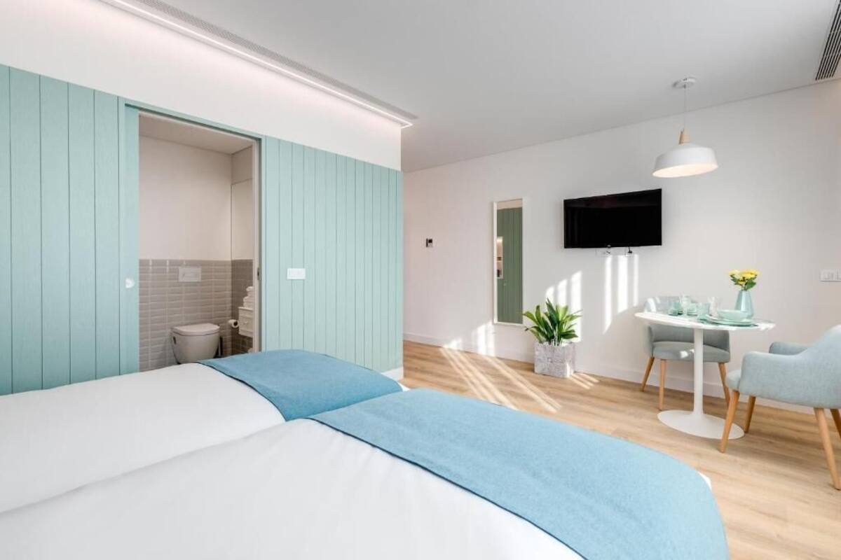 Ein modernes Hotelzimmer mit Bett, Schreibtisch, Fernseher und Essbereich.