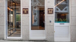 A building facade with three distinct entrances, each marked by a sign. The left entrance is labeled "MERNA-NAU," the middle one "7BRIDGES," and the right one "48." - 7 Bridges Estúdios (Porto)