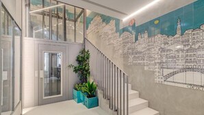 A modern staircase with a cityscape mural, a glass door, and potted plants. - 7 Bridges Estúdios (Porto)