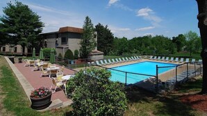 Una piscina con sillas de descanso y un patio con mesas y sillas.