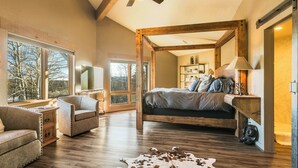 A spacious bedroom with a large bed, a ceiling fan, and a view of the outdoors through large windows. - Elevated Home w/Hot Tub, Beautiful Views, Firepit, 3 King Bedrooms, Bunkroom (Angel Fire)