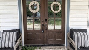 A double door with two wreaths, a bench with striped cushions, and a gravel path. - ⭐️Rustic Hill Country Barn retreat on acreage⭐️ (San Marcos)