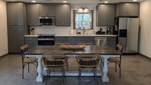 A modern kitchen with grey cabinets, a central island with chairs, and built-in appliances. - ⭐️Rustic Hill Country Barn retreat on acreage⭐️ (San Marcos)