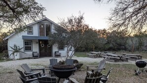 A house with a gravel yard, outdoor seating with Adirondack chairs, a fire pit, and picnic tables. - ⭐️Rustic Hill Country Barn retreat on acreage⭐️ (San Marcos)