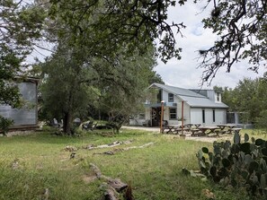 A rustic house with a porch, outdoor seating, and a cactus in the foreground.
