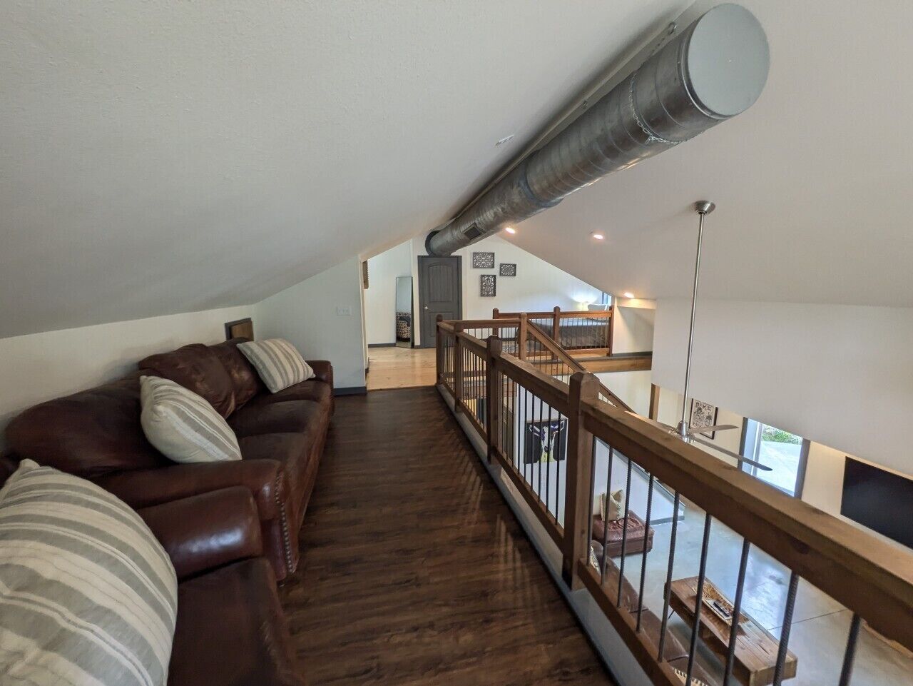 Un espacio habitable tipo loft con una escalera de madera, un sofá de cuero y vistas a la cocina.