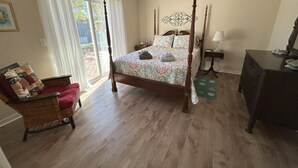 A bedroom with a four-poster bed, a wicker chair, a dresser, and a ceiling fan. - Tranquility awaits, close to Wrightsville beach & downtown Riverwalk! (Wilmington)