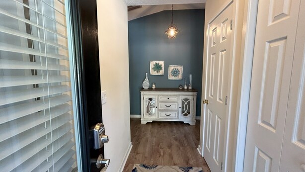 A hallway with a patterned rug, a white cabinet with decorative items, and a door with a keyhole. - Tranquility awaits, close to Wrightsville beach & downtown Riverwalk! (Wilmington)