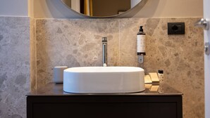 A bathroom with a round mirror, a white sink, and a marble-tiled wall. - Your room like in a 4-star Hotel (Roma)