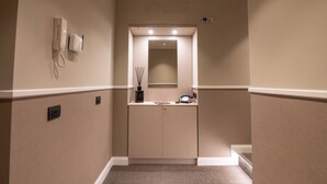 A hallway with a phone, a mirror, and a small table with a magazine and a bottle. - Your room like in a 4-star Hotel (Roma)