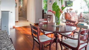 Une salle à manger spacieuse avec un plafond haut, un plancher en bois et une grande table ronde placée au centre, entourée de chaises.