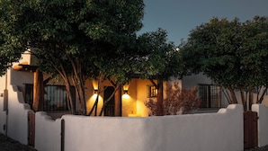 A stucco house with a white exterior, a wooden fence, and trees.