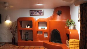 A room with a unique orange wall design, a fireplace, a yellow armchair, and a small plant on a shelf.
