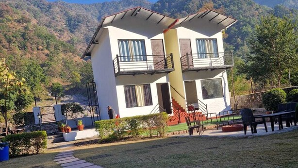 A two-story building with a balcony, surrounded by a well-maintained garden and a stone pathway leading to the entrance. - Camp Aquaforest  (Rishikesh)