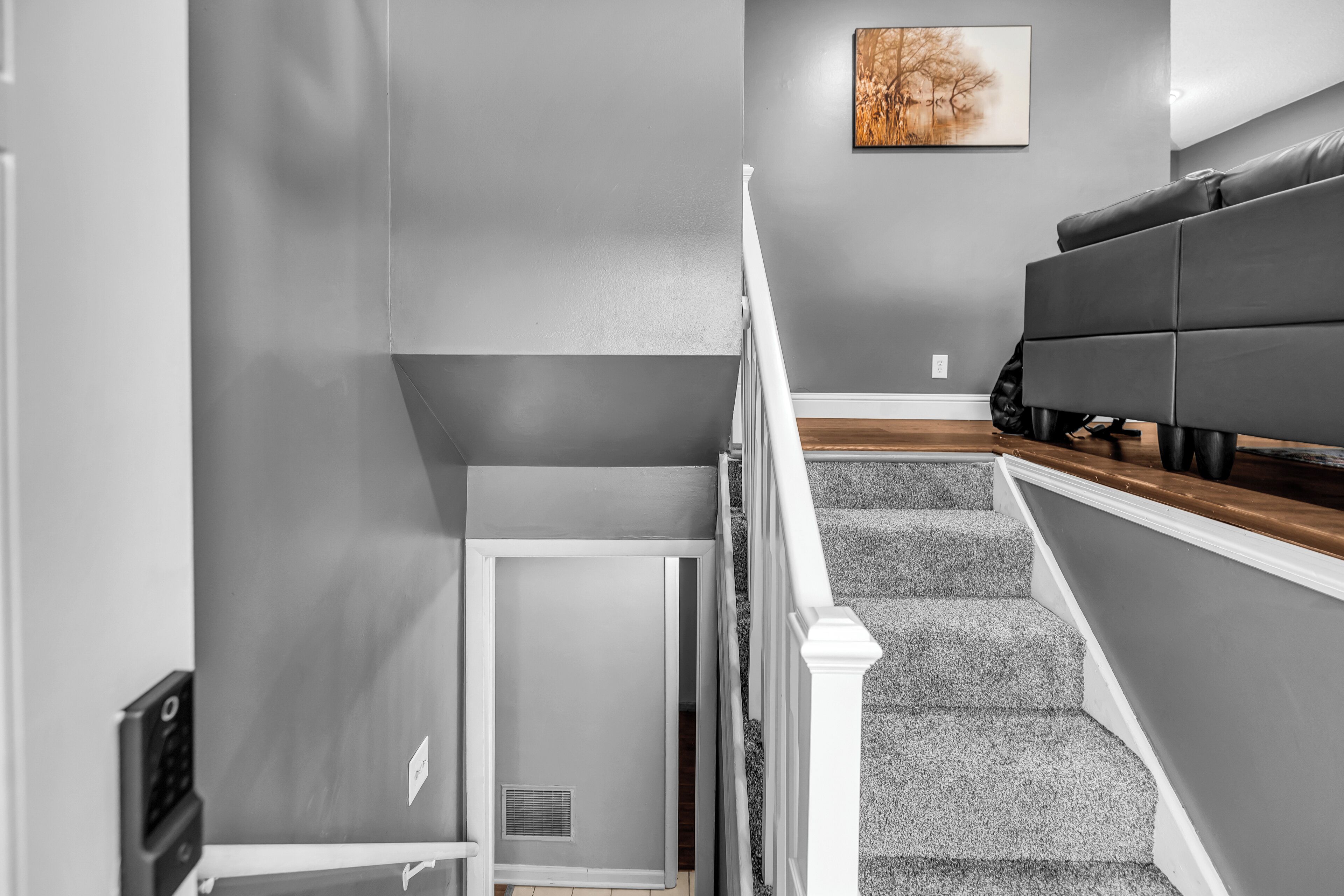 A staircase with a white railing, grey walls, and a grey carpeted floor.