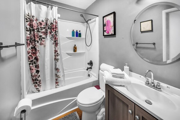 Un baño con bañera, inodoro, lavabo y cortina de ducha.