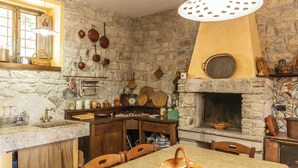 A rustic kitchen with stone walls, a wooden table, and a hanging light fixture. - Villa Paradiso - Irpinia (Gesualdo)