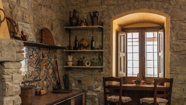 A rustic kitchen with stone walls, wooden furniture, and shelves with kitchenware. - Villa Paradiso - Irpinia (Gesualdo)