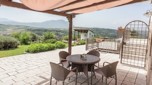 A patio with wicker furniture, a table, and a view of the countryside. - Villa Paradiso - Irpinia (Gesualdo)