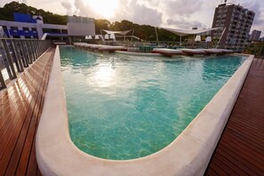 Une piscine avec une terrasse en bois et des chaises longues.
