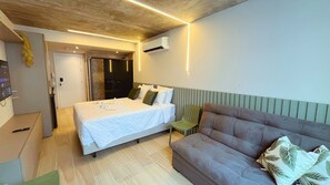 Una habitación de hotel moderna con una cama, una silla verde y un sofá.