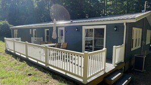 Une petite maison mobile d’un seul étage, dotée d’un porche couvert et d’une petite terrasse.