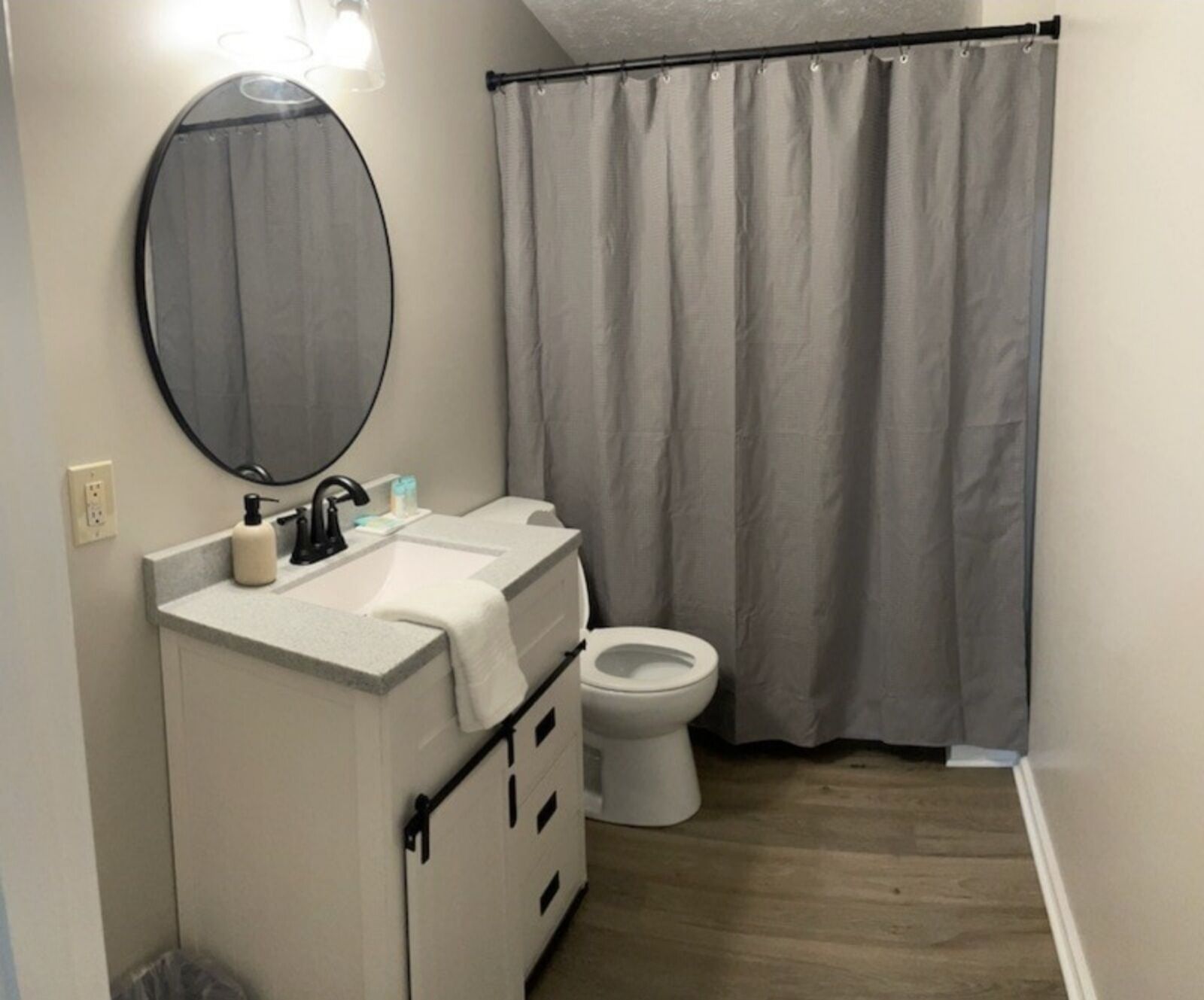 A bathroom with a white sink, a mirror, a toilet, and a shower curtain.