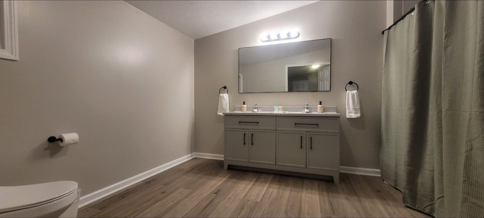 Un baño con inodoro, lavabo con espejo y cortina de ducha.