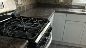 A kitchen with a gas stove, oven, and white cabinets.