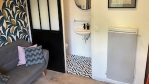 A modern bathroom with a white sink, a mirror, and a radiator. - Le Merle Rose, house with garden, quiet and close to the center (Toulouse)