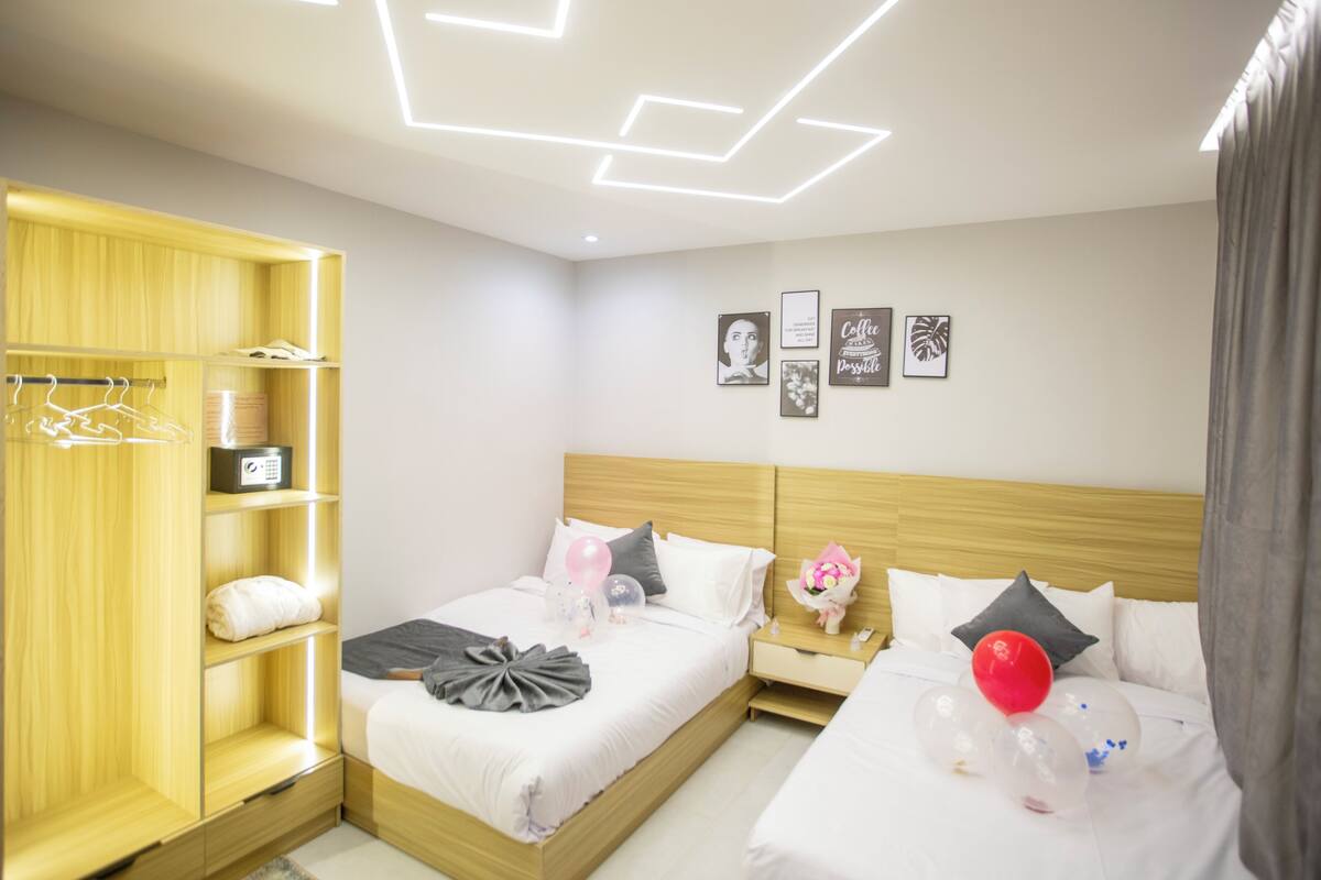 Ein modernes Hotelzimmer mit einem Holzschrank, einem Bett mit weißer Bettwäsche, einem Nachttisch mit Lampe und einer Wand mit gerahmten Bildern.