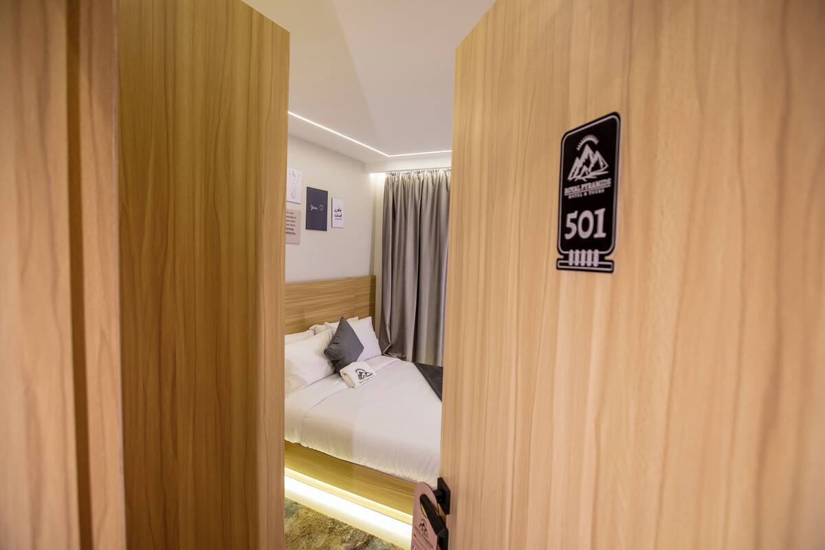 Ein Hotelzimmer mit einem Bett, einem Schild mit der Zimmernummer 501 und Blick auf den Flur.