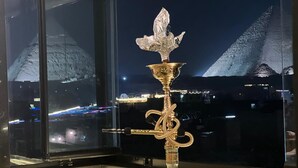 A hookah on a table near a window with a view of a pyramid and city lights. - Royal Pyramids View Inn (Giza)