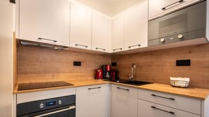 A compact kitchen with white cabinets, a black oven, a stainless steel range hood, a wooden countertop, a sink, and a coffee maker. - 15m from ski slopes, 1st floor, view mountain, balcony, tv, ski locker, 49m², Valmorel (Valmorel)