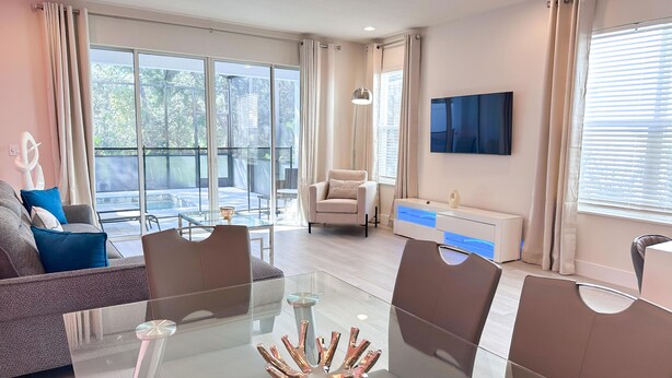 A modern living room with a glass coffee table, a sofa, and a TV mounted on the wall.