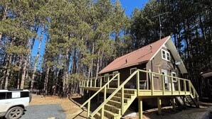 Une cabane dotée d’une terrasse en bois et d’un escalier menant à un porche abrité.