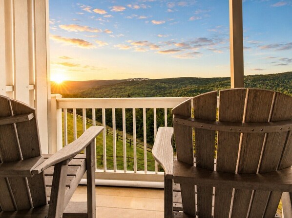 A wooden deck with two Adirondack chairs, a white railing, and a scenic view of a forested landscape during sunset. - ML288 New Deck Great Views EZ Parking WiFi Retreat (Snowshoe)
